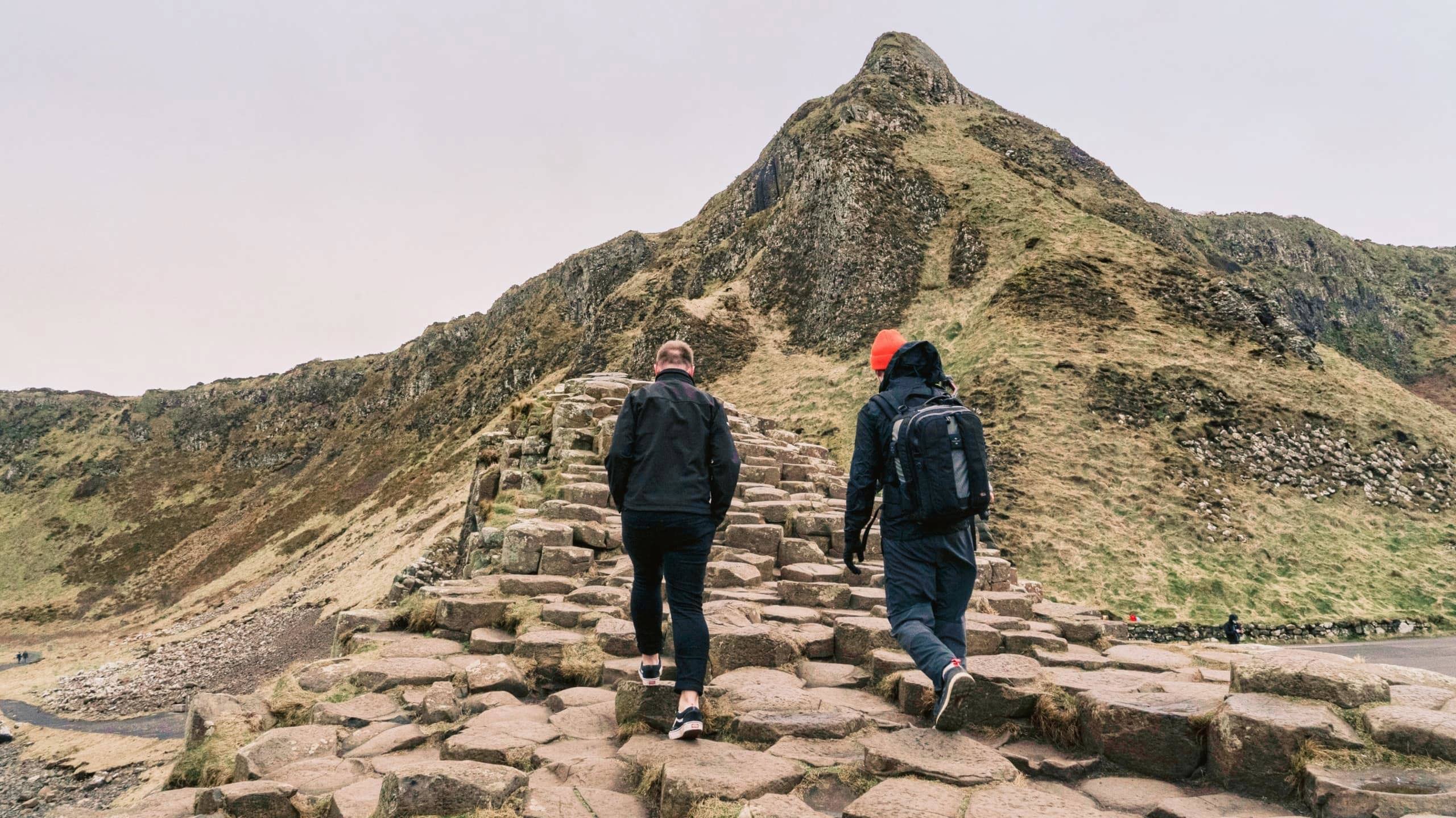 Travellers walking across the Giant's Causeway basalt columns in County Antrim, Northern Ireland, on the Contiki Ireland in a Week 35 to 45 Tour