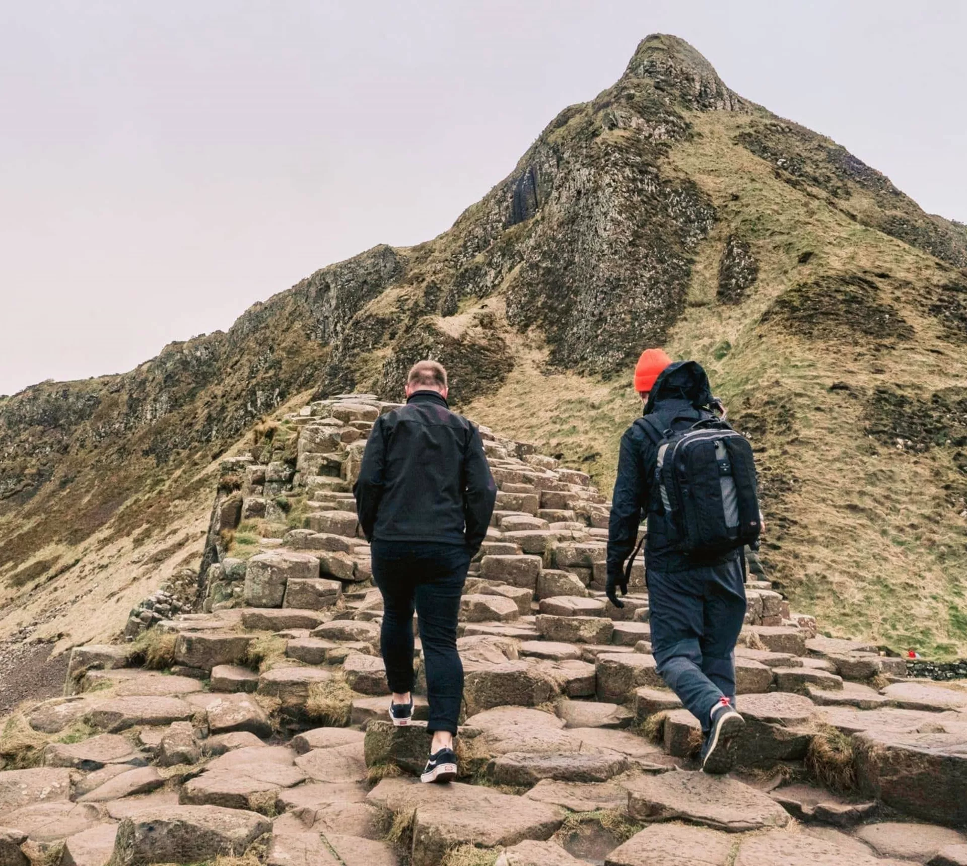 Travellers walking across the Giant's Causeway basalt columns in County Antrim, Northern Ireland, on the Contiki Ireland in a Week 35 to 45 Tour
