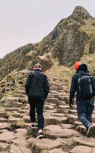 Travellers walking across the Giant's Causeway basalt columns in County Antrim, Northern Ireland, on the Contiki Ireland in a Week 35 to 45 Tour