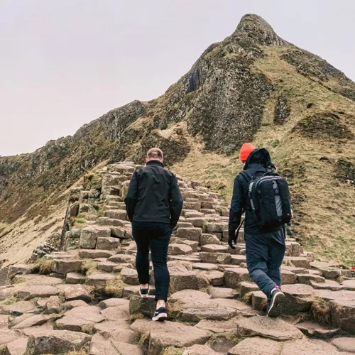 Travellers walking across the Giant's Causeway basalt columns in County Antrim, Northern Ireland, on the Contiki Ireland in a Week 35 to 45 Tour