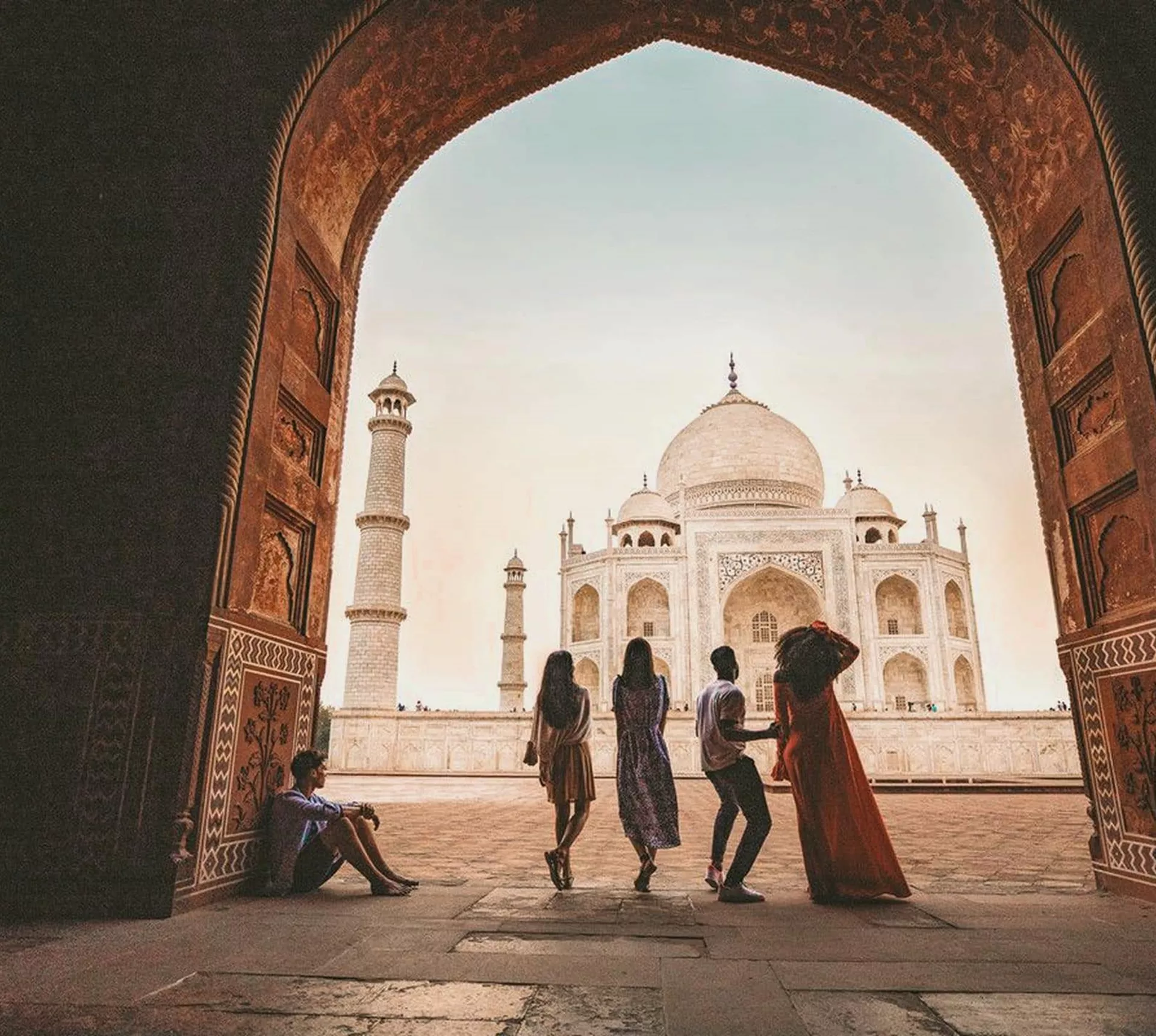 Travellers framed through the ornate Great Gate archway looking towards the Taj Mahal white marble mausoleum in Agra India - Contiki Eternal India Tour