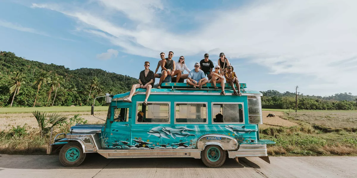 Group Of Young Travelers Sitting On Top Of Cool Bus Philippines