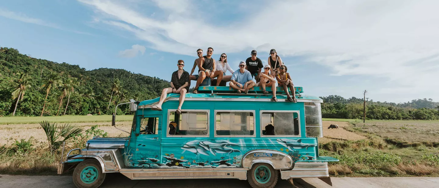 Group Of Young Travelers Sitting On Top Of Cool Bus Philippines