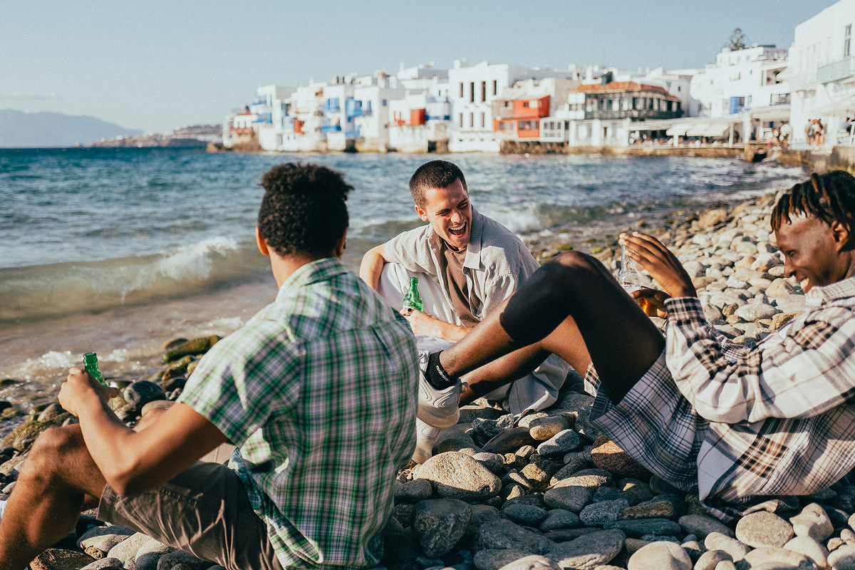 Friends Drinking Beers On The Beach At Sunset In Mykonos Greece