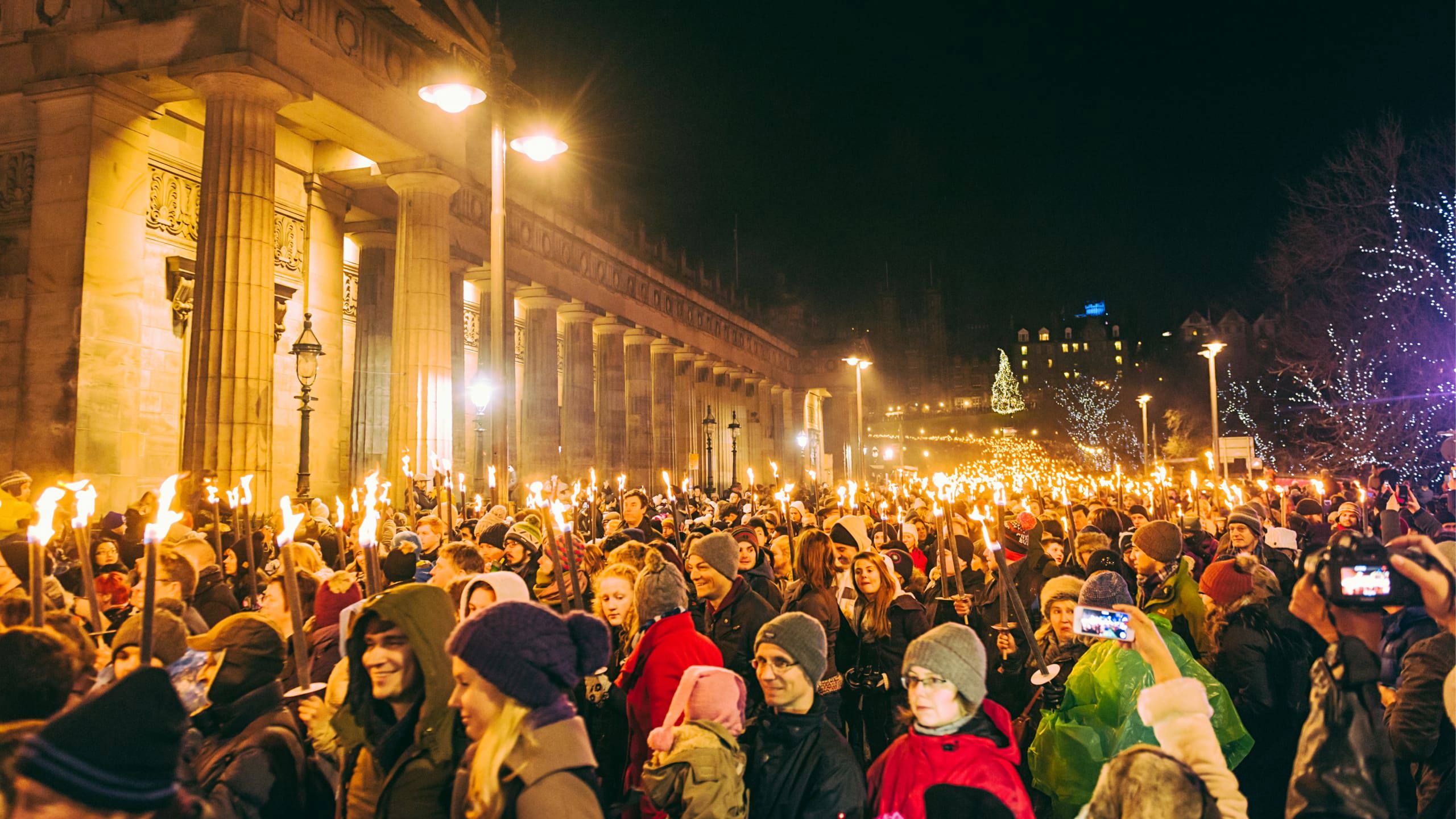 Contiki travellers joining the famous Edinburgh Hogmanay Torchlight Procession with thousands of torch-bearing revellers outside the Royal Scottish Academy at night