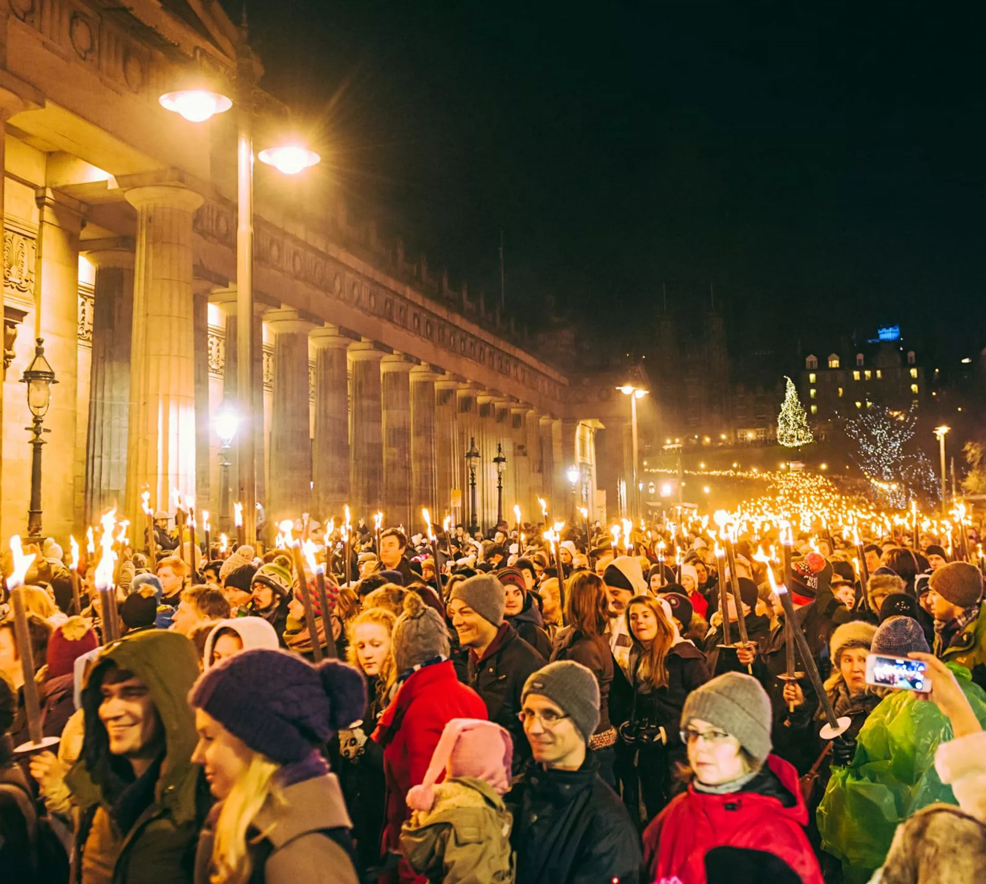 Contiki travellers joining the famous Edinburgh Hogmanay Torchlight Procession with thousands of torch-bearing revellers outside the Royal Scottish Academy at night