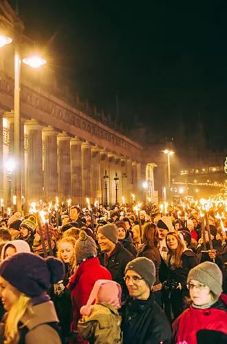 Contiki travellers joining the famous Edinburgh Hogmanay Torchlight Procession with thousands of torch-bearing revellers outside the Royal Scottish Academy at night