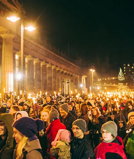 Contiki travellers joining the famous Edinburgh Hogmanay Torchlight Procession with thousands of torch-bearing revellers outside the Royal Scottish Academy at night