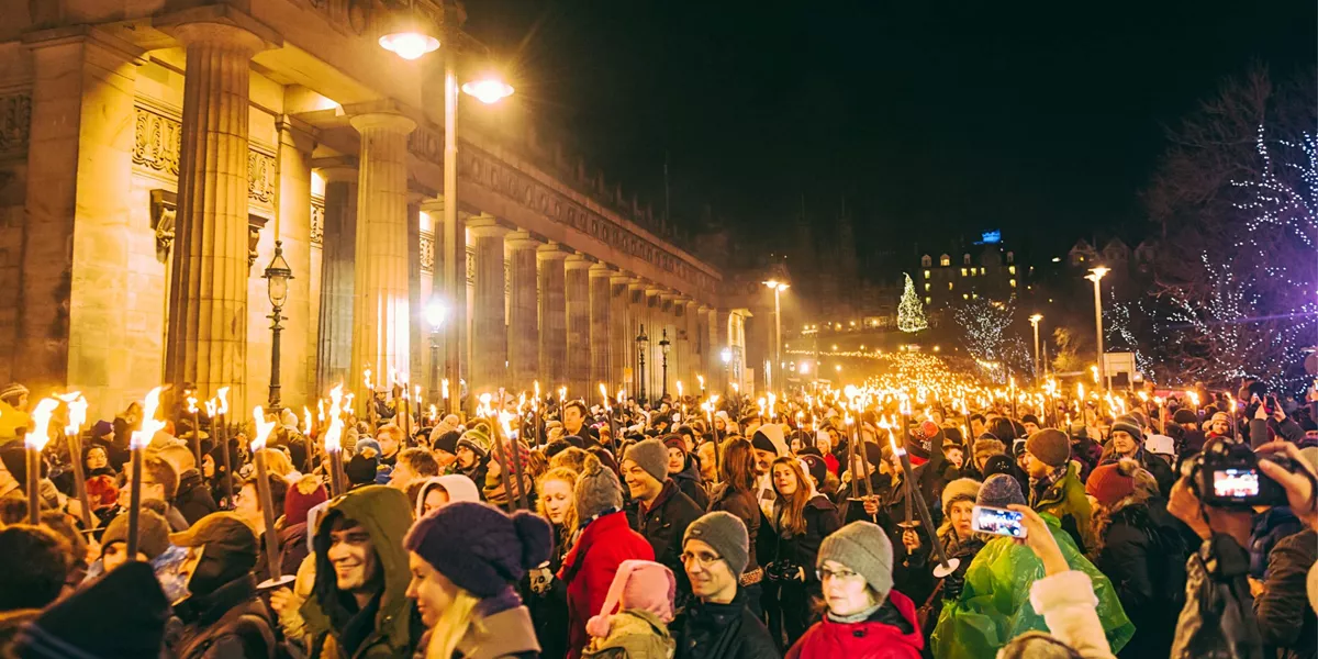 Contiki travellers joining the famous Edinburgh Hogmanay Torchlight Procession with thousands of torch-bearing revellers outside the Royal Scottish Academy at night
