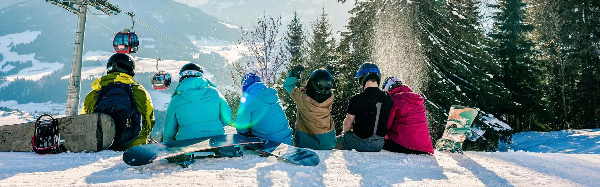 Friends sitting on the snow looking at snowy mountains in Austria.