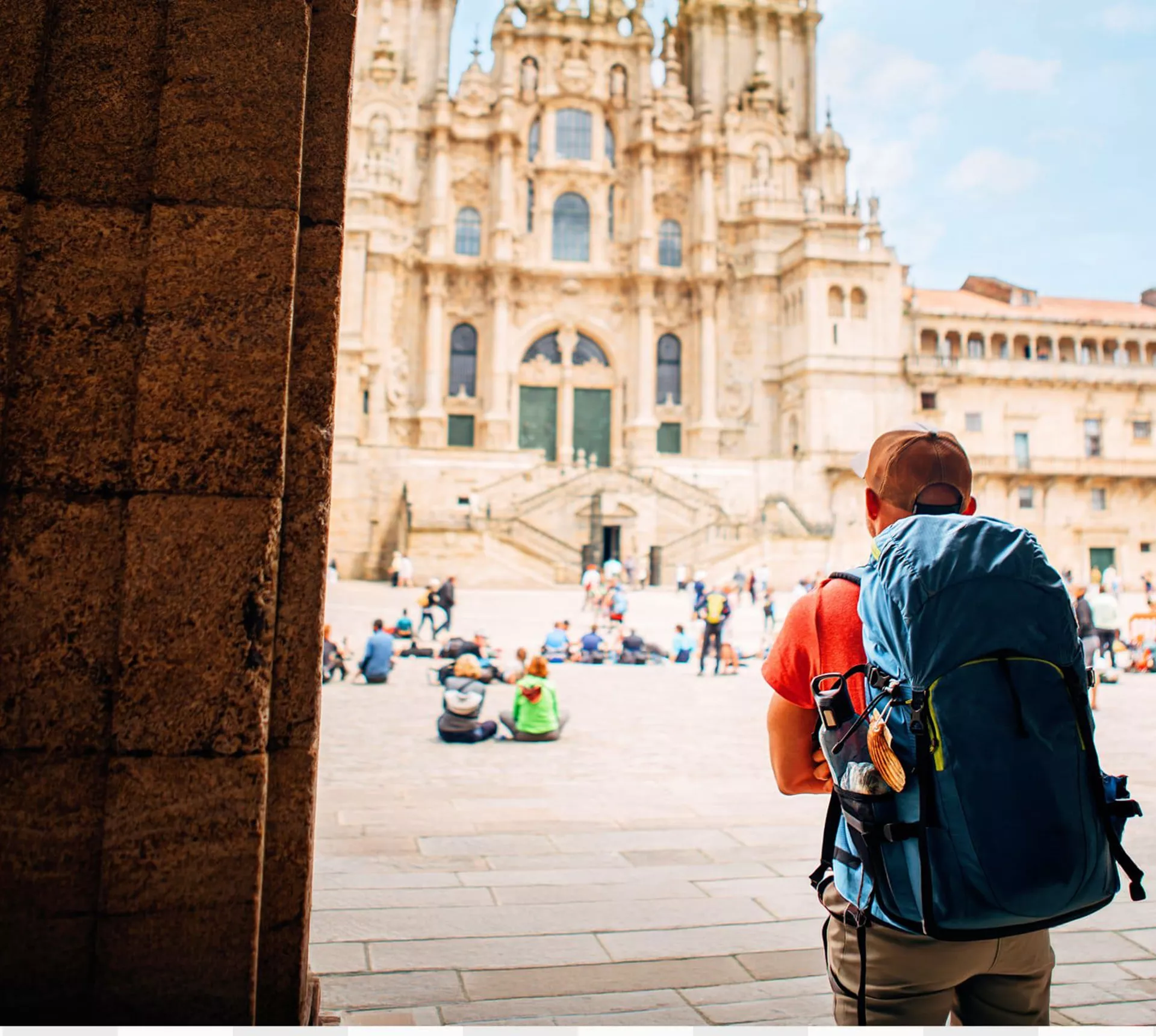 Hiker with backpack arriving at the Cathedral of Santiago de Compostela and Plaza del Obradoiro at the end of the Camino de Santiago Spain - Contiki Hiking Camino Tour