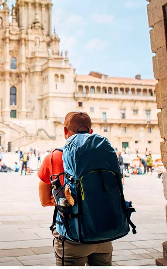 Hiker with backpack arriving at the Cathedral of Santiago de Compostela and Plaza del Obradoiro at the end of the Camino de Santiago Spain - Contiki Hiking Camino Tour