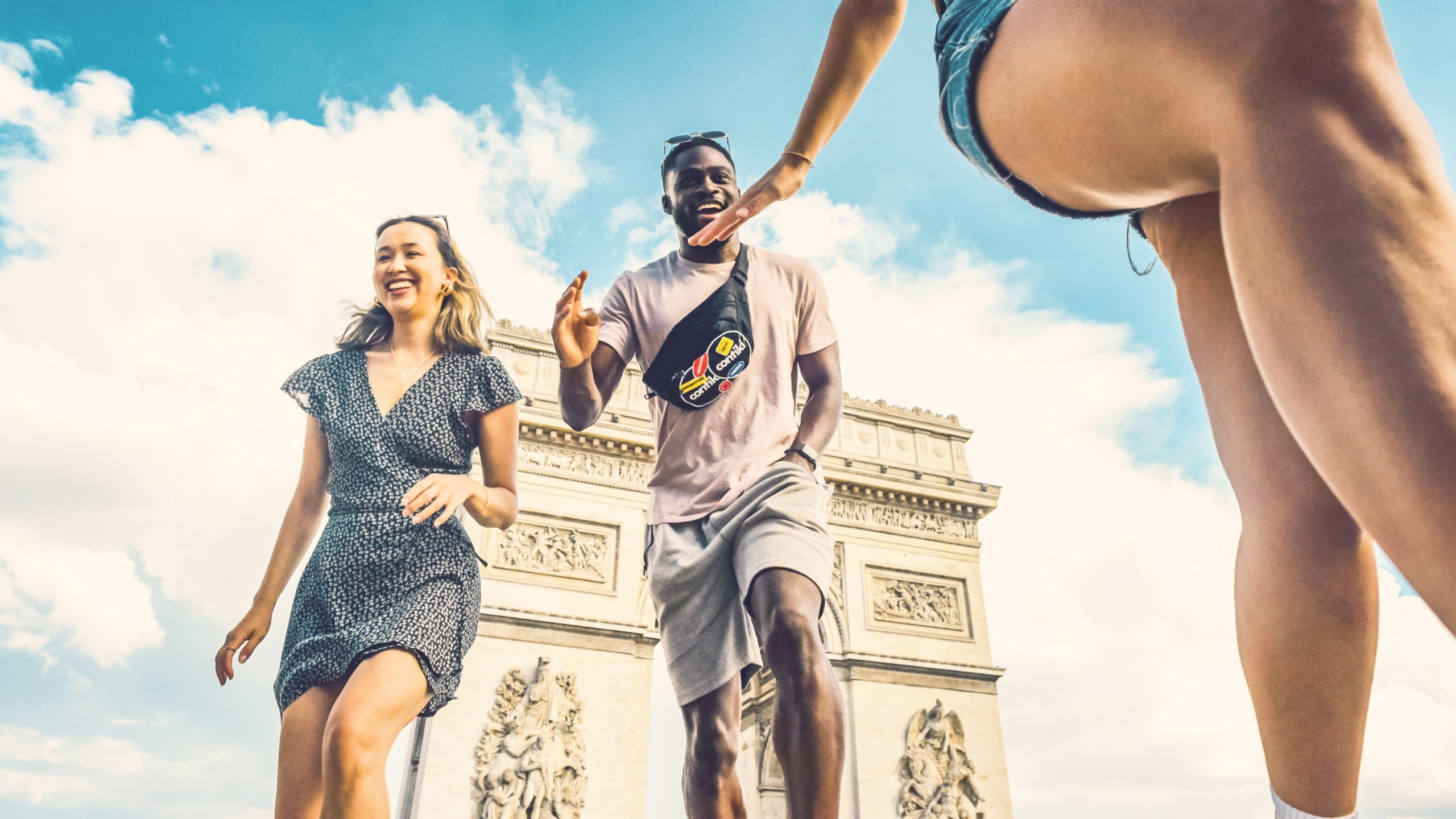 Contiki travellers laugh and high-five in front of the Arc de Triomphe in Paris during the London to Athens Tour