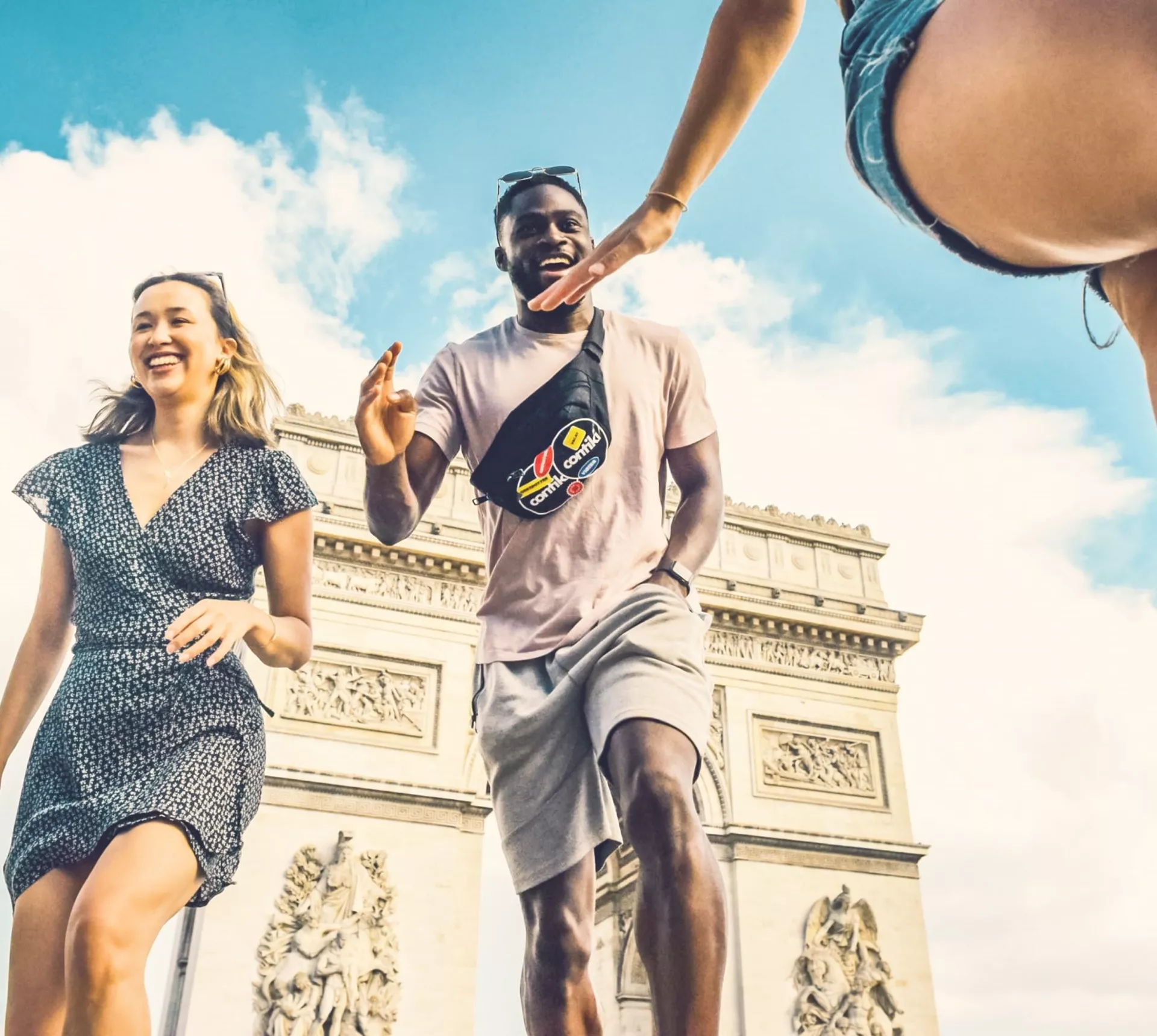Contiki travellers laugh and high-five in front of the Arc de Triomphe in Paris during the London to Athens Tour