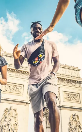 Contiki travellers laugh and high-five in front of the Arc de Triomphe in Paris during the London to Athens Tour