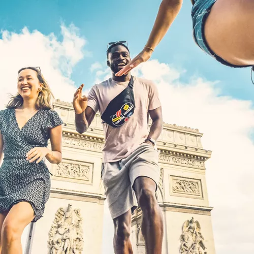 Contiki travellers laugh and high-five in front of the Arc de Triomphe in Paris during the London to Athens Tour