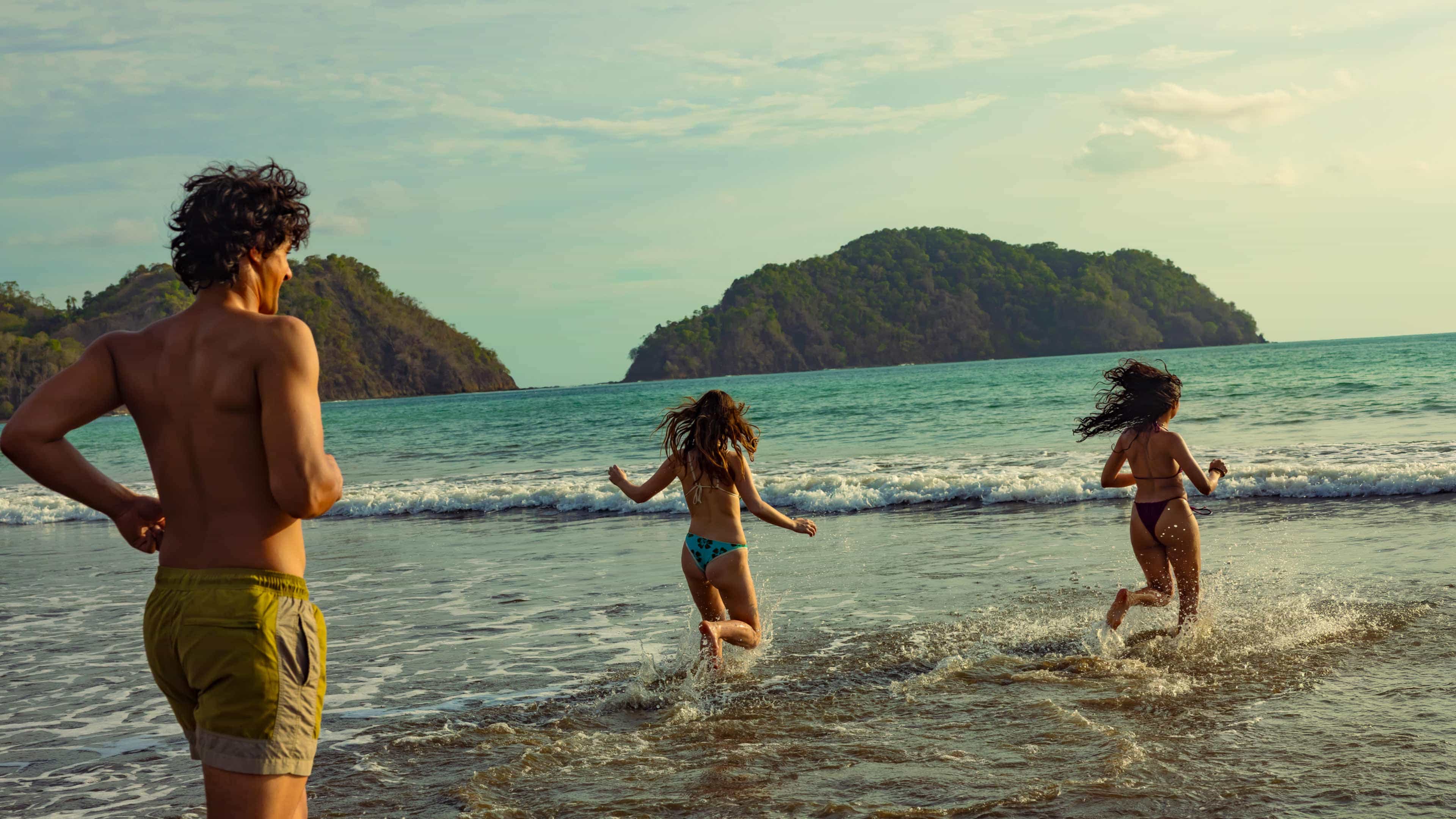 Contiki travellers run into the ocean waves on a jungle-fringed beach in Costa Rica.