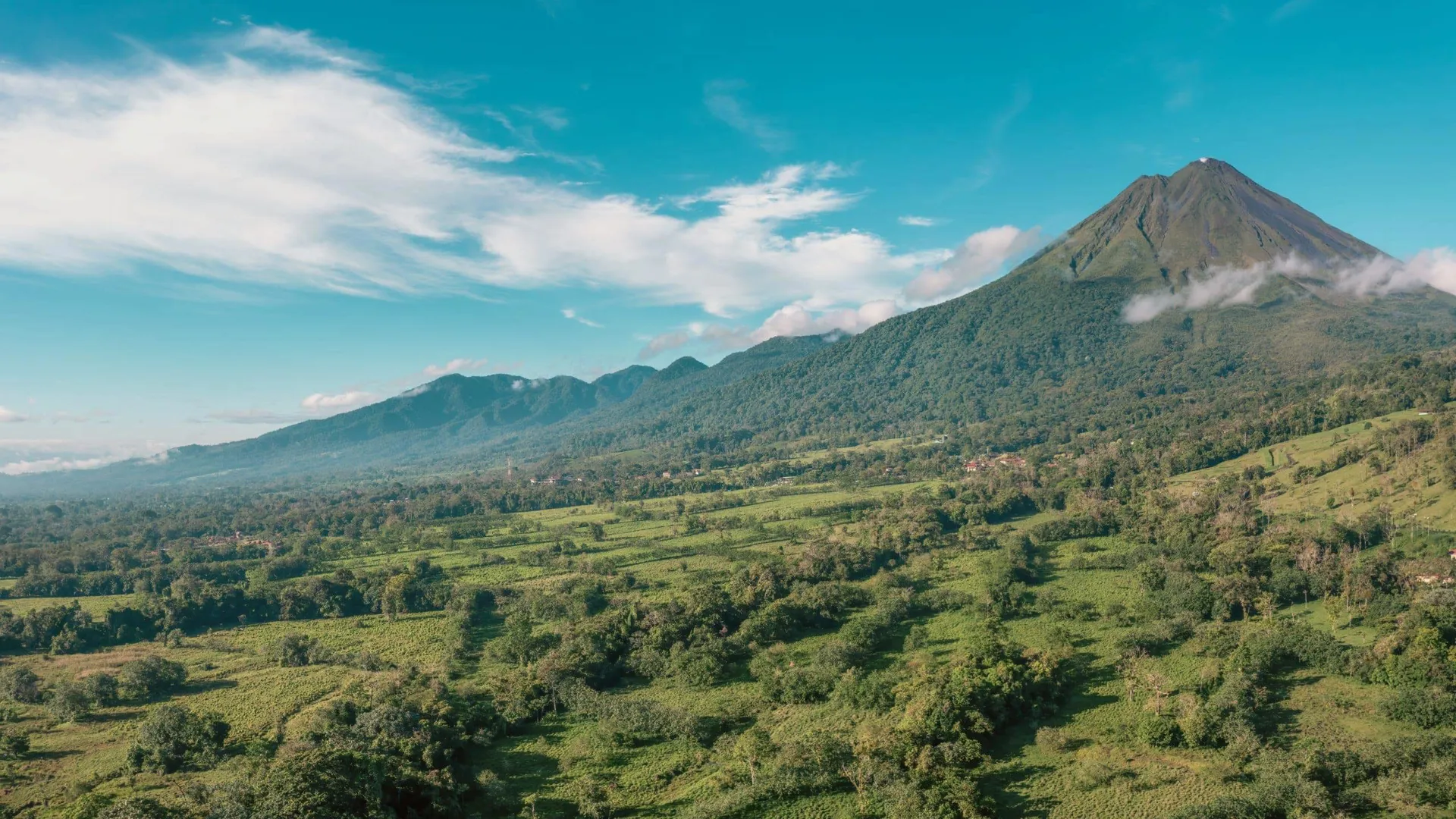 Arenal Volcano towers over lush, green hills in Costa Rica.