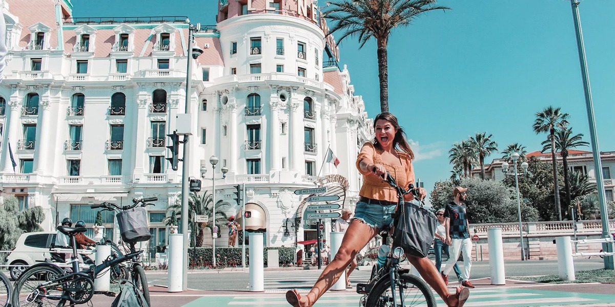 Woman riding a bike with a landmark as background in France.