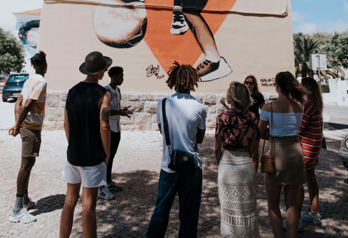 A group of people standing in front of a mural
