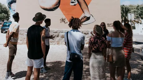 A group of people standing in front of a mural