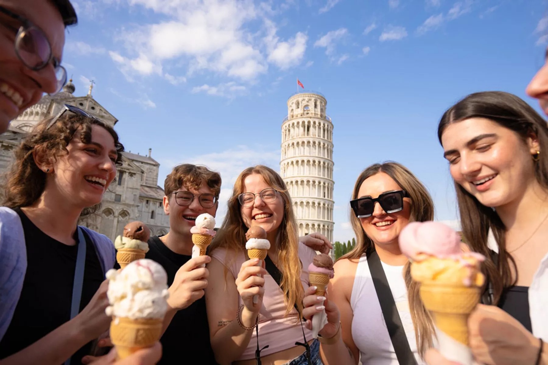 Group Of Friends Enjoying Ice cream in front of leaning tower of Pisa in Italy