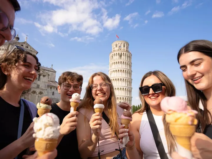 Group Of Friends Enjoying Ice cream in front of leaning tower of Pisa in Italy