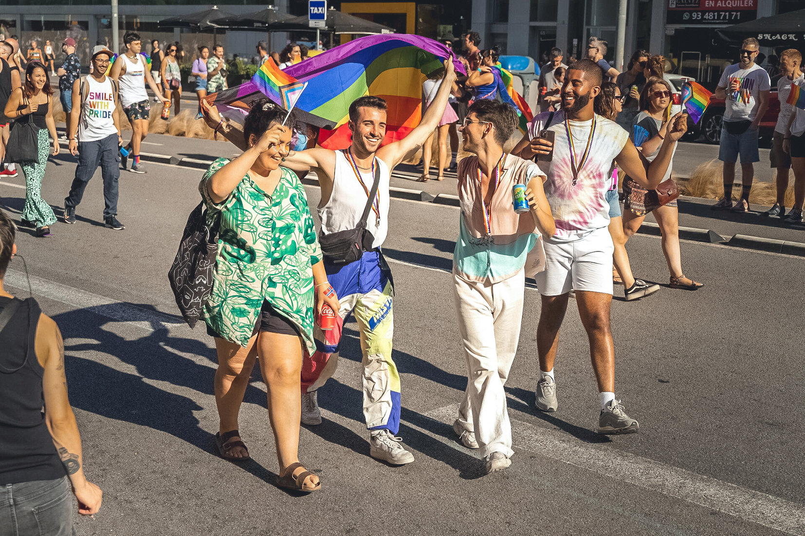 Four travellers holding up a Pride flag whilst walking in a parade in Athens, Greece
