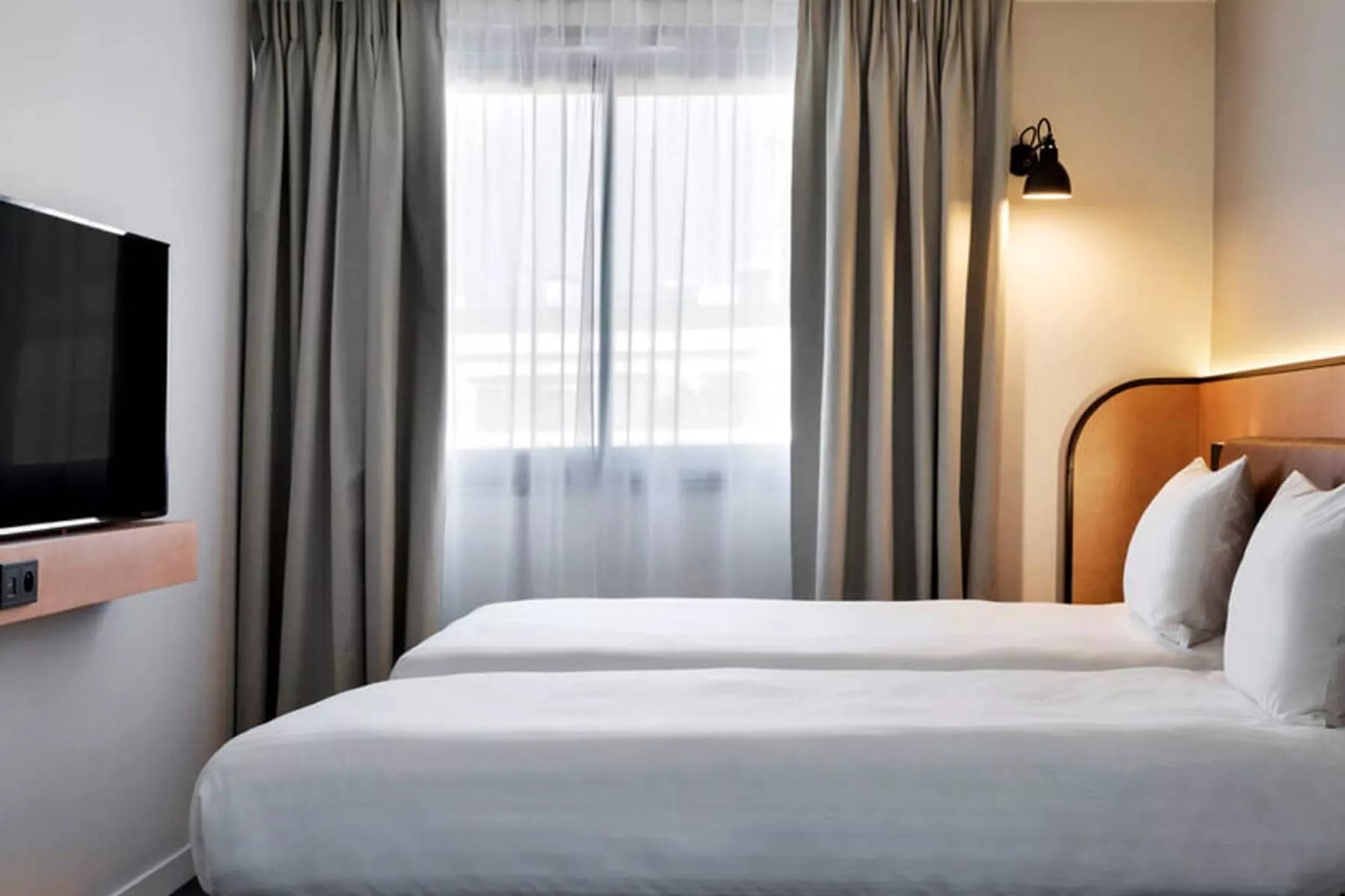 Moxy Paris Bastille bedroom bed with white sheets and wall tv
