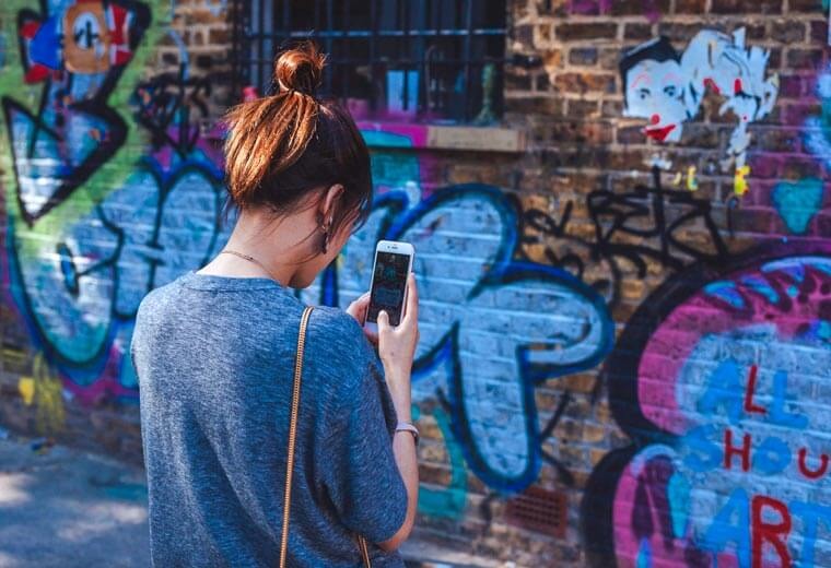 Young woman taking photo of graffiti on phone