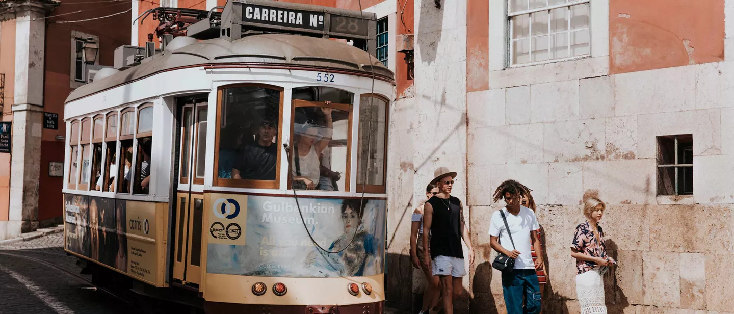 Group Walking Next To Tram In Portugal