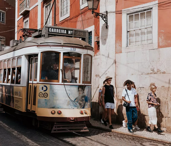 Group Walking Next To Tram In Portugal
