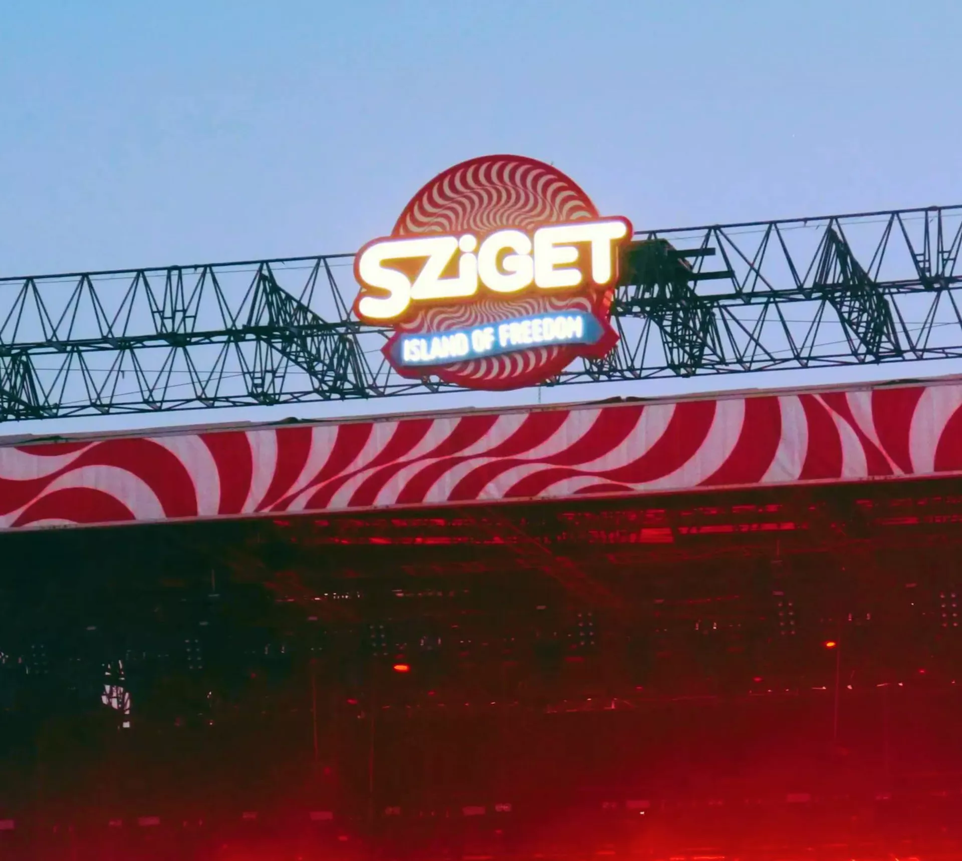Sziget Festival main stage at dusk in Budapest Hungary with illuminated logo and red swirl stage design - Contiki Europe Festival Tour