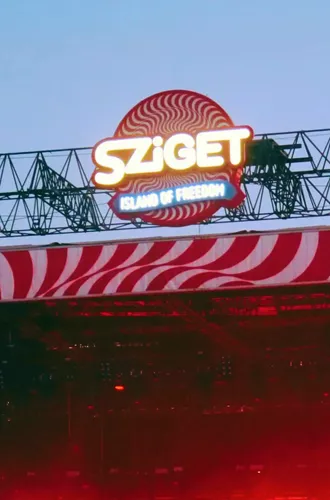 Sziget Festival main stage at dusk in Budapest Hungary with illuminated logo and red swirl stage design - Contiki Europe Festival Tour