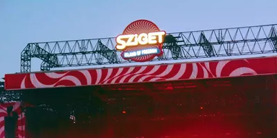 Sziget Festival main stage at dusk in Budapest Hungary with illuminated logo and red swirl stage design - Contiki Europe Festival Tour