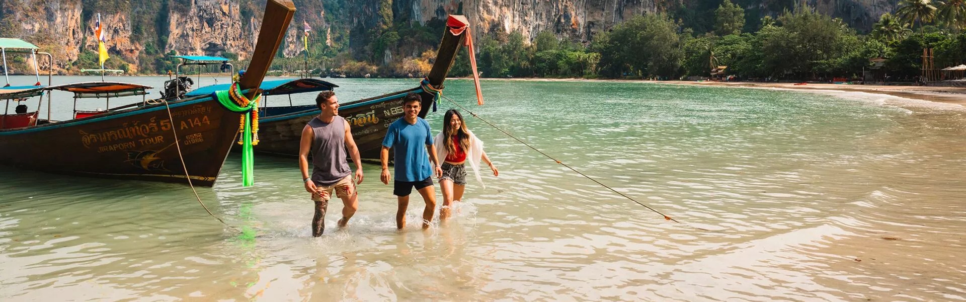 Three friends walking out of the sea on a sunny day in Thailand.