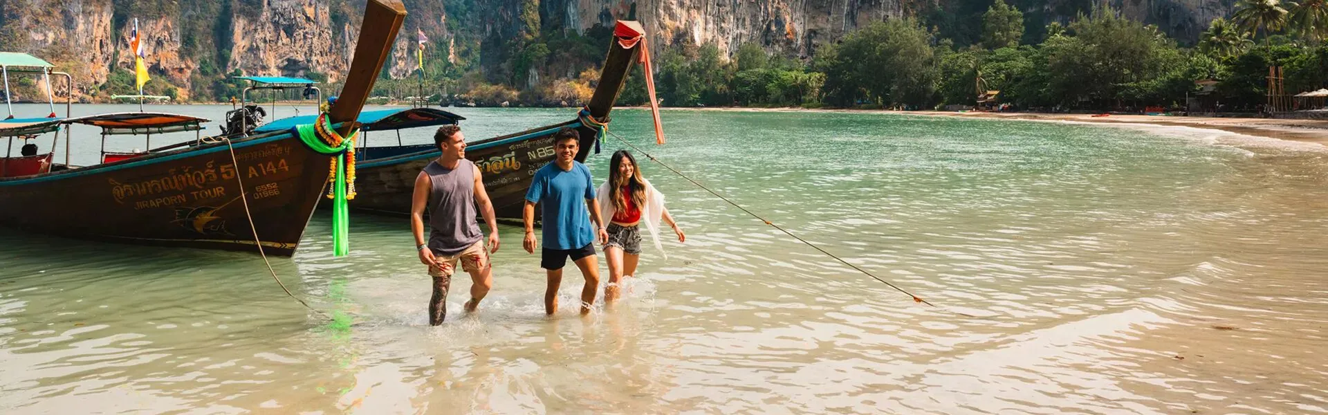 Three friends walking out of the sea on a sunny day in Thailand.