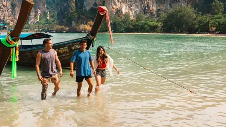 Three friends walking out of the sea on a sunny day in Thailand.