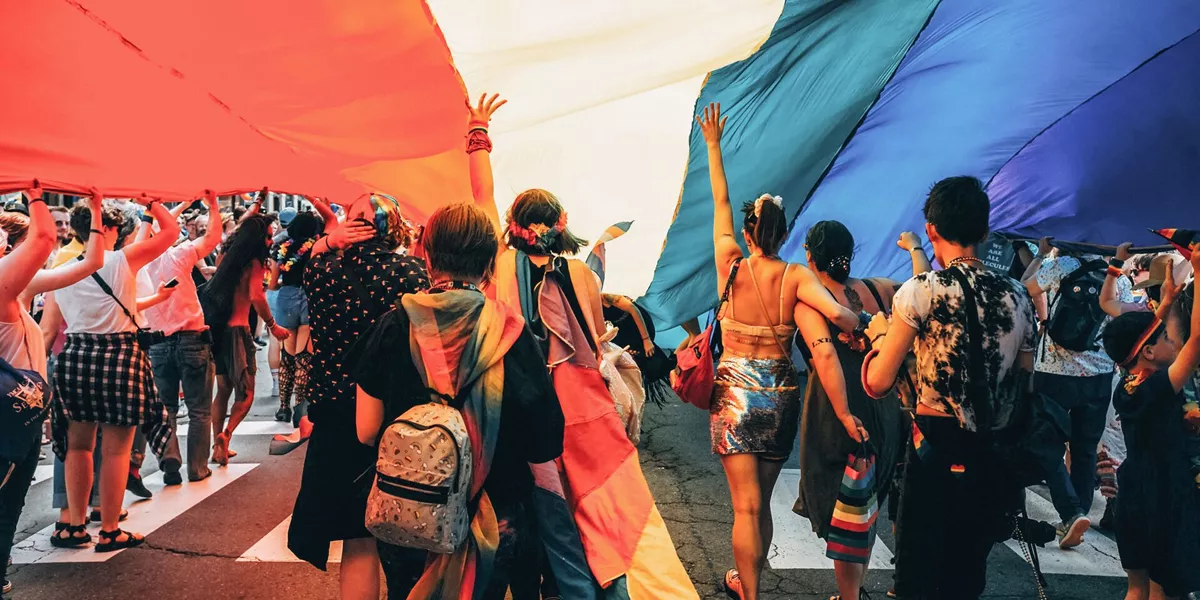 Travellers at the Pride festival holding a big rainbow flag