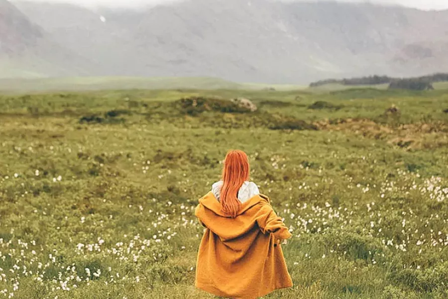 Red-haired girl walking on the meadow
