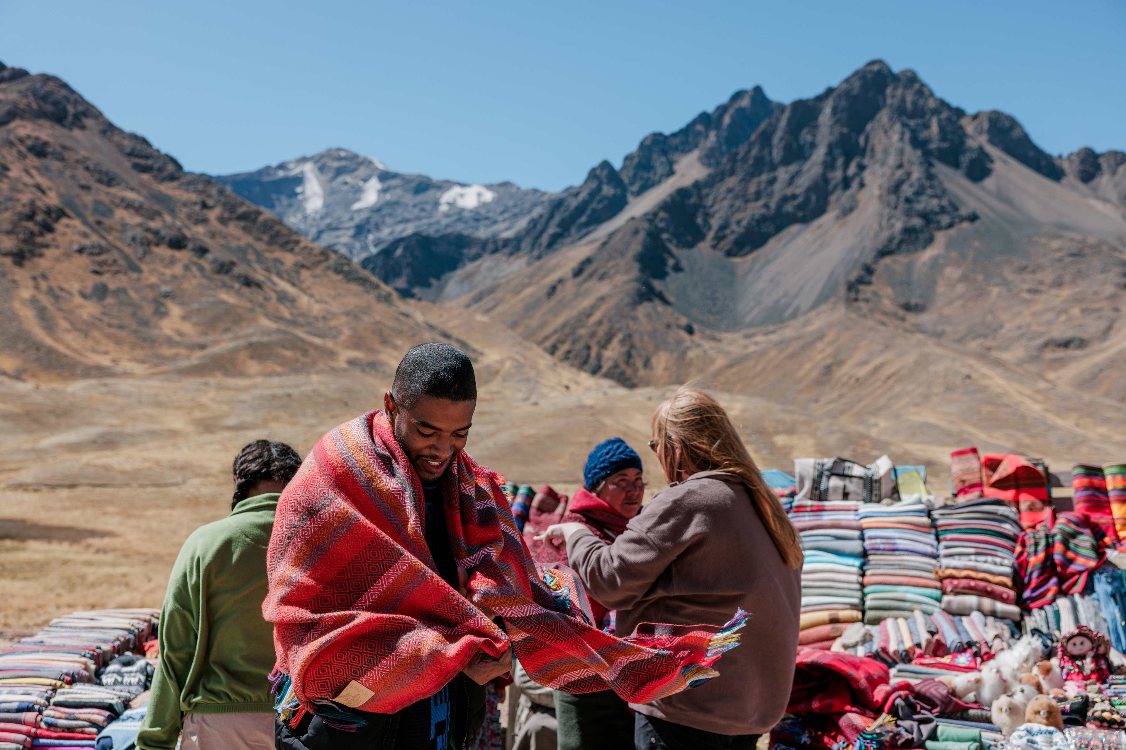Person Wearing A Poncho Local Sellers Showing Their Different Ponchos As Background