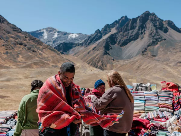Person Wearing A Poncho Local Sellers Showing Their Different Ponchos As Background