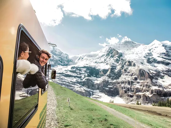 Two Young Happy People Enjoying The Snowy Mountains View From A Train