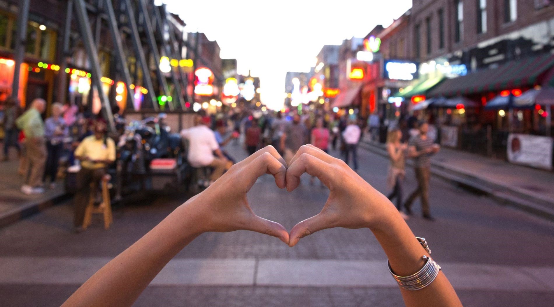 Hands forming heart shape on crowded Toronto Street in Canada