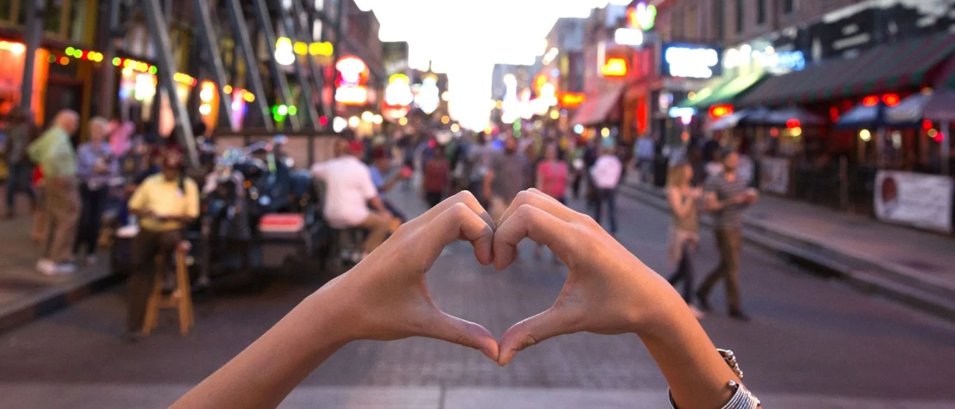 Hands forming heart shape on crowded Toronto Street in Canada