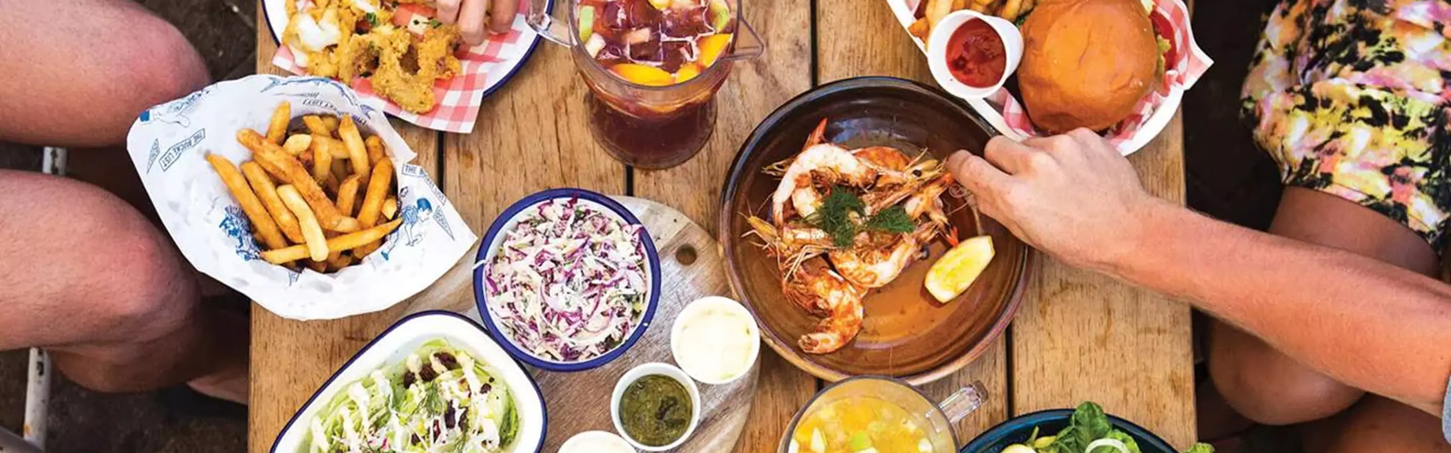 Wooden table full of various traditional local Australian dishes