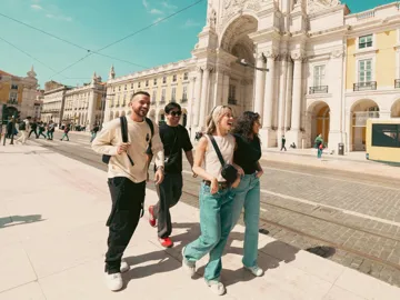 Contiki travellers exploring Lisbon’s Praça do Comércio beside the iconic yellow tram, discovering historic landmarks on the Spain & Portugal Panorama Tour