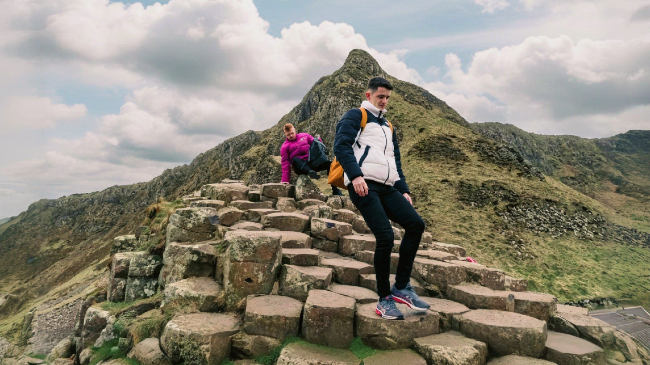 Travellers explore the Giant's Causeway, with its iconic basalt columns and dramatic coastal landscape, on the Contiki Best of Great Britain & Ireland Tour