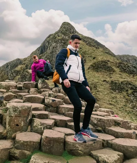 Travellers explore the Giant's Causeway, with its iconic basalt columns and dramatic coastal landscape, on the Contiki Best of Great Britain & Ireland Tour