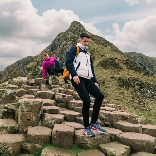 Travellers explore the Giant's Causeway, with its iconic basalt columns and dramatic coastal landscape, on the Contiki Best of Great Britain & Ireland Tour